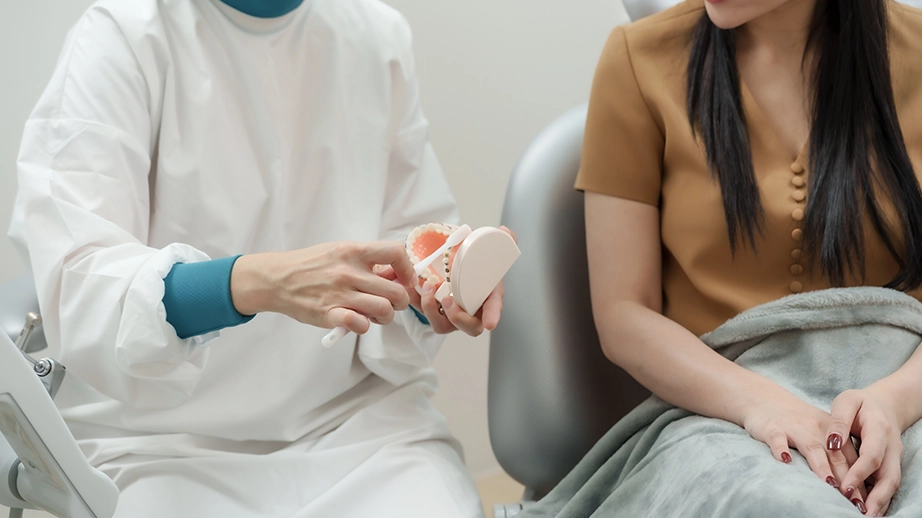 Dentist using toothbrush on dental model to show correct brushing technique to patient
