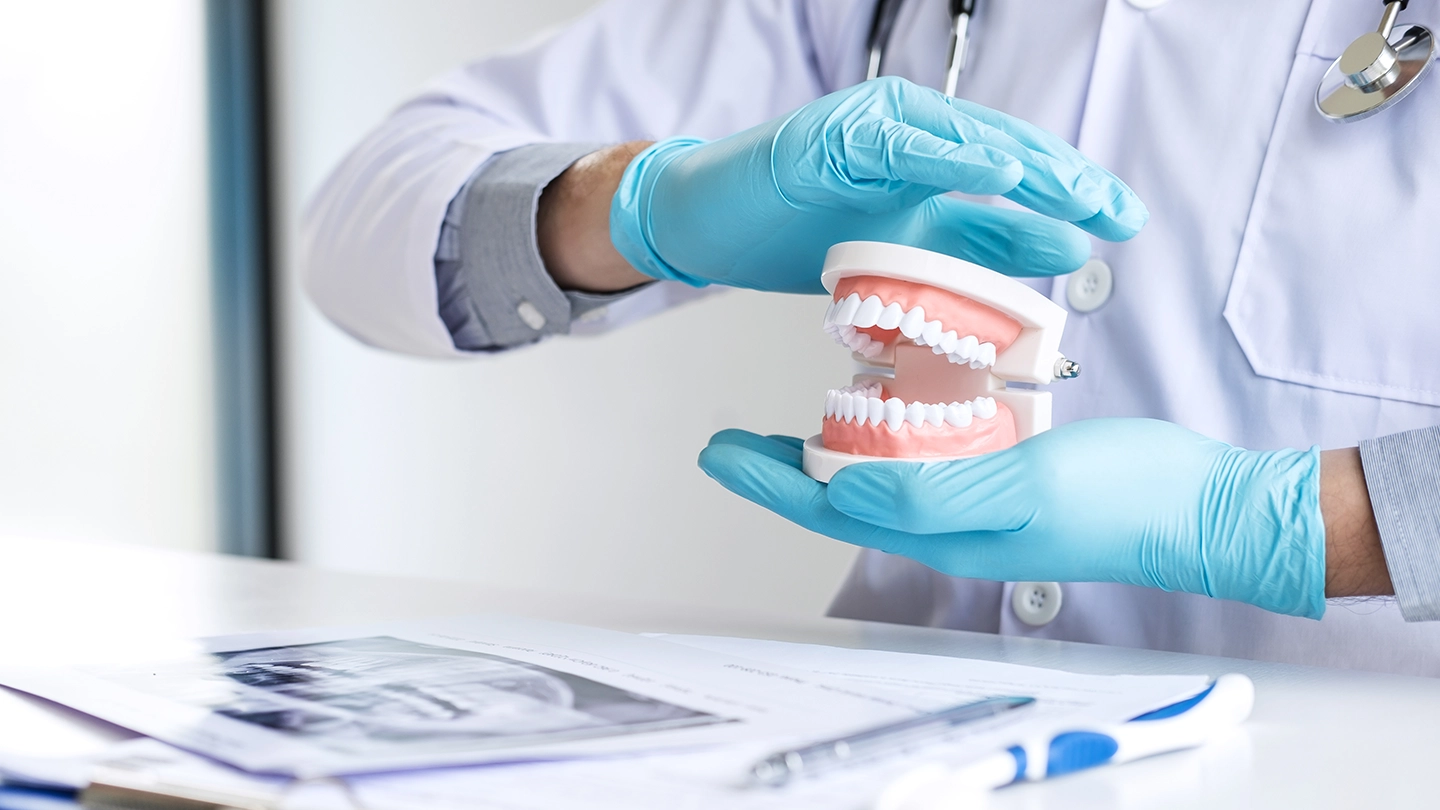 Dental specialist using a tooth model to explain treatments for overbite and underbite.