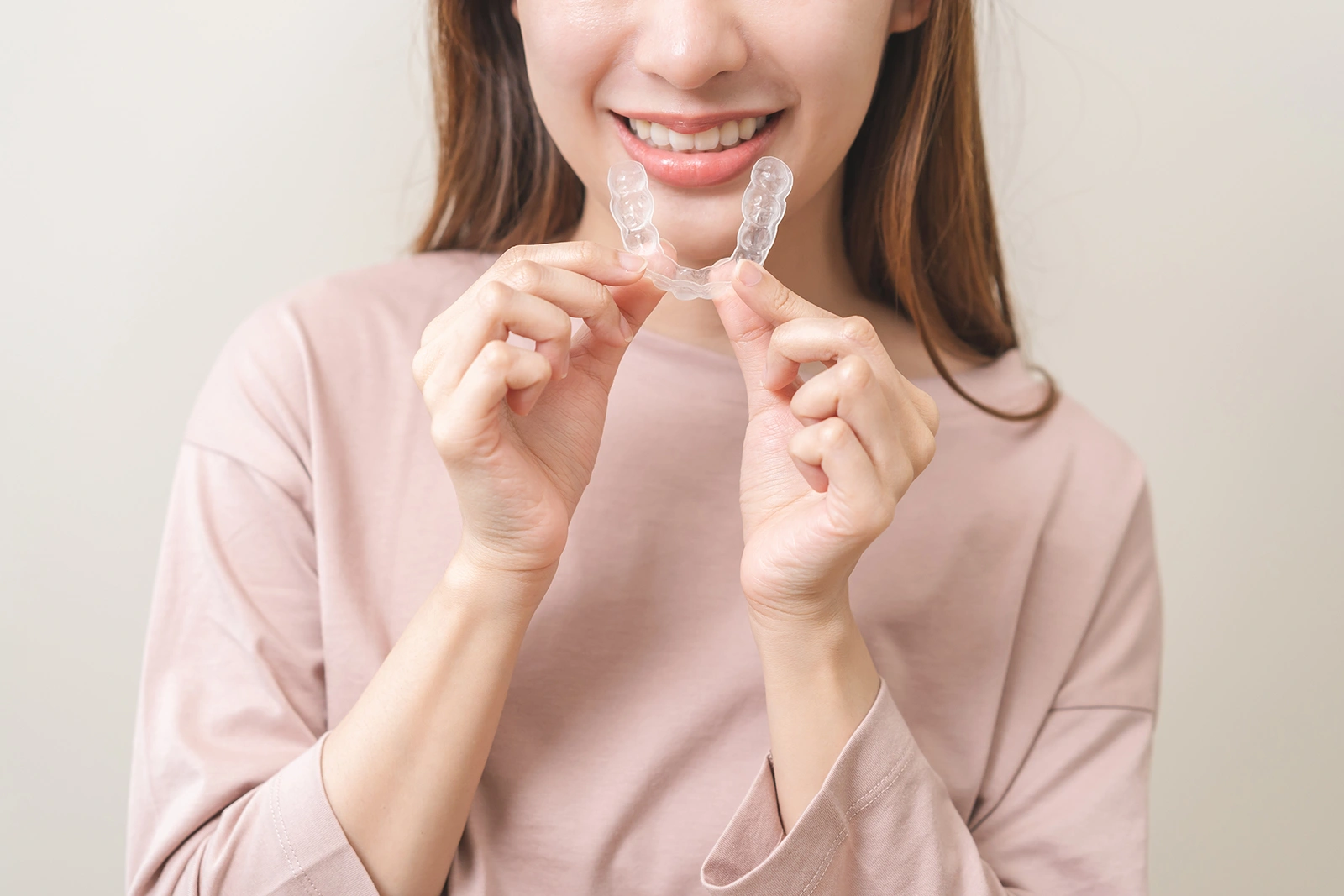 Woman holding Invisalign clear aligners