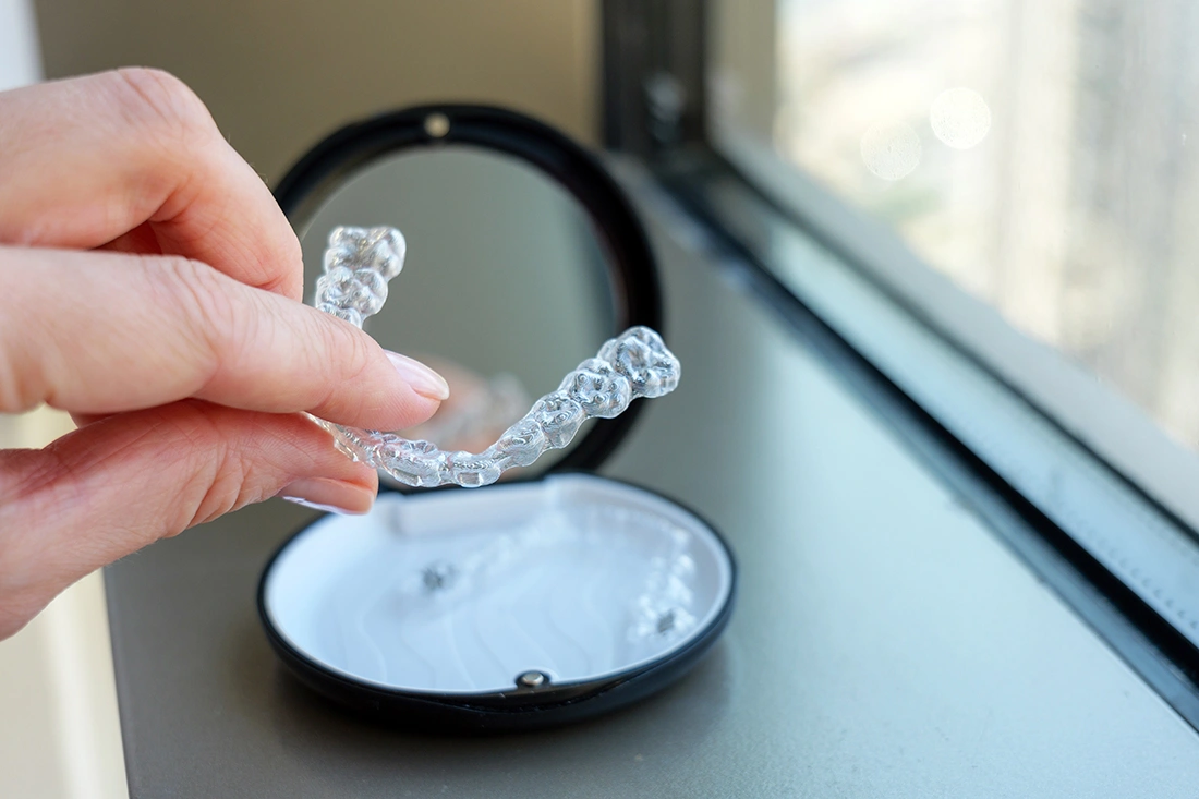 Close up of a hand taking a clear aligner out of its casing