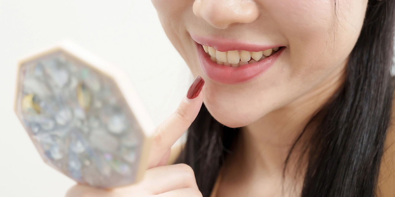 A woman inspecting her teeth after Invisalign treatment